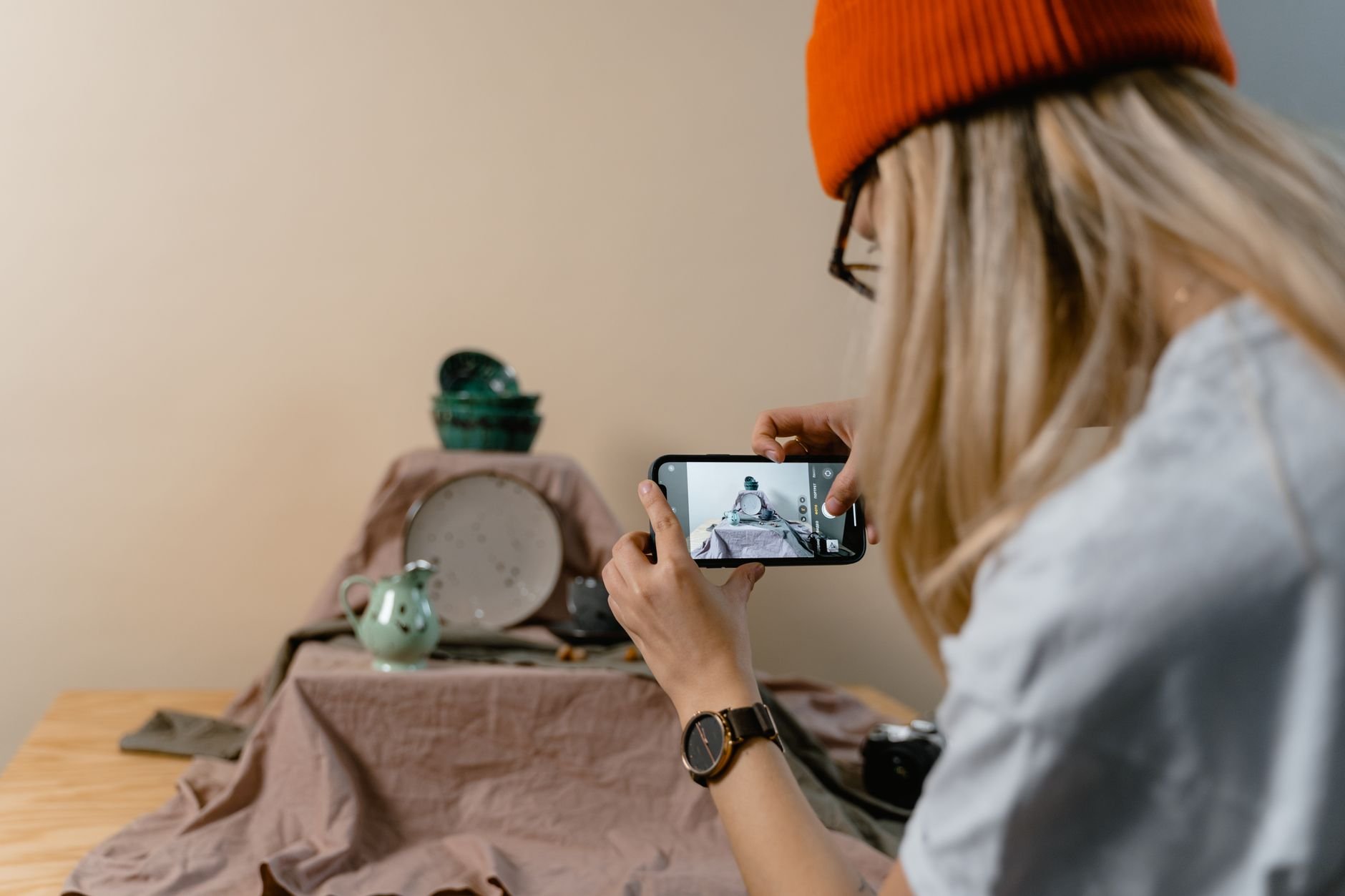 A woman uses a smartphone to photograph tableware, the kind of seller workflow SnapSell AI is built for